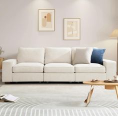 a living room with a white couch and two pictures on the wall next to it