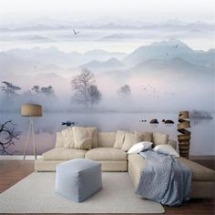 a living room with a large couch in front of a wall mural that has birds flying over the water