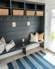 a bench with baskets on it in front of a wall mounted coat rack and door