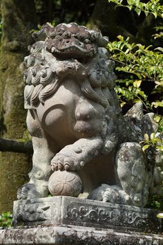 a stone lion statue in front of some trees