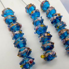 several blue glass beads are lined up next to each other on a white table top