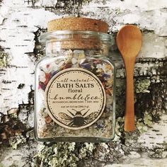 a jar filled with bath salts next to a wooden spoon