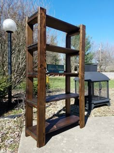 a wooden shelf sitting on top of a sidewalk next to a lamp post and tree