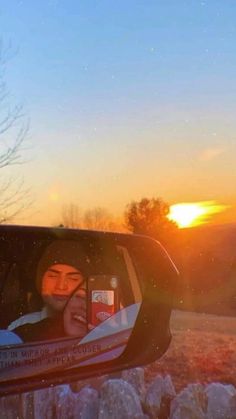 the reflection of a person in a car's side view mirror at sunset or dawn