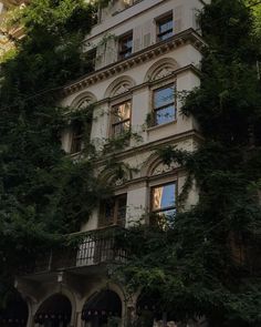 an old building with ivy growing on it's side and windows in the front