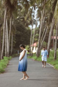 a pregnant woman standing in the middle of a road with her husband walking behind her