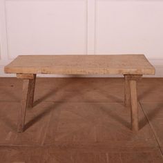 a wooden bench sitting on top of a hard wood floor next to a white wall