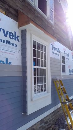 a house being built with new windows and siding on the side of it, next to a yellow ladder