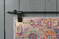 a multicolored rug hanging on the side of a wooden wall next to a metal hook