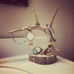 a wooden stand with watches and bracelets sitting on top of a white bathroom sink