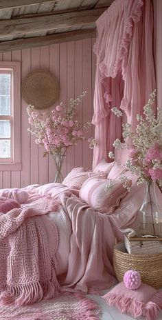 a bed with pink sheets and pillows in a room next to a basket filled with flowers