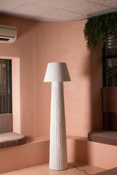 a white lamp sitting on top of a table next to a window with pink walls