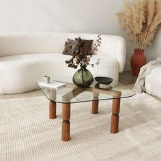 a glass table sitting on top of a white rug in a living room next to a couch