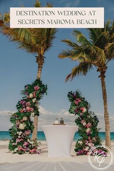 an outdoor ceremony set up on the beach with flowers and palm trees in the background