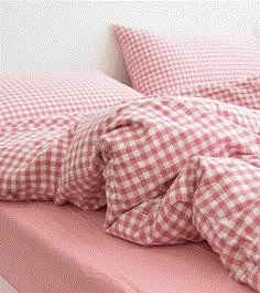 an unmade bed with red and white checkered sheets