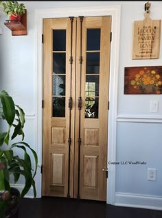 two wooden doors in the corner of a room with potted plants on either side