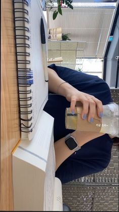 a woman sitting at a desk with a bottle in her hand and an apple watch on her wrist