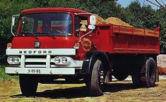 an old red dump truck parked in the dirt