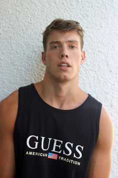 a young man in a tank top poses for the camera