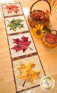 the table runner is decorated with autumn leaves and sunflowers, along with two baskets of flowers