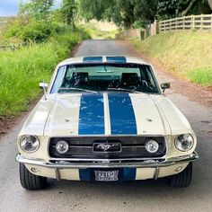 a blue and white mustang sitting on the side of a road