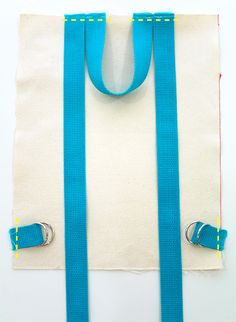 a pair of blue suspenders hanging from a white bag with yellow stitching on it