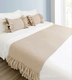 a bed with ruffled sheets and pillows on it