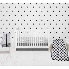 a white crib with black polka dots on the wall next to it and a baby's bed