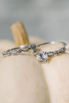 two wedding rings sitting on top of a white pumpkin