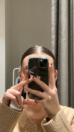 a woman taking a selfie in front of a mirror with her cell phone up to her face