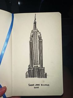 an open notebook with a drawing of the empire state building