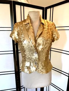 Vintage gold sequin jacket, cropped sequin jacket by Twelfth Street NWT. Please zoom in for details, photos are part of description. This flashy gold sequin top has elastic cap sleeves, two faux front pockets and shell buttons for closure. Label states 100% silk size medium, please go by measurements provided. In very good condition, no holes or stains. Measurements taken with garment lying flat  Shoulder: 15" Bust: 19" underarm to underarm ( 38" doubled ) Waist: 15" seam to seam ( 30" doubled ) Fitted Sequin Outerwear For Holidays, Gold Outerwear For Night Out And Party Season, Gold Outerwear For Party Season Night Out, Gold Outerwear For Party Season And Night Out, Glamorous Gold Fitted Outerwear, Gold Sequined Outerwear For Spring, Fitted Gold Outerwear For Holiday, Gold Festive Outerwear For Spring, Embellished Gold Outerwear For Spring