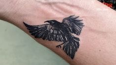 a black bird tattoo on the arm of a man's left arm and wrist