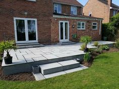 a patio with steps leading up to the back door and lawn area next to it