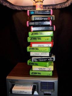 a stack of books sitting on top of a radio in front of a wall light