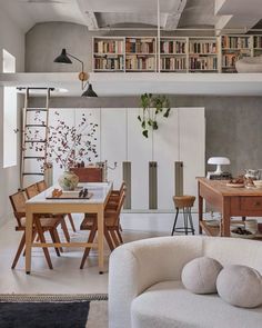 a living room filled with lots of furniture and bookshelves above a dining table