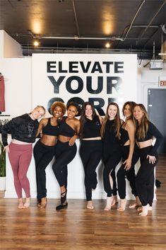 a group of women standing next to each other in front of a sign that says elevate your body