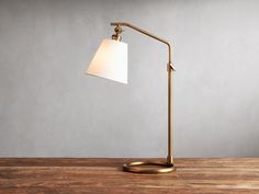 a lamp that is on top of a wooden table in front of a gray wall