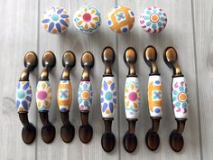 six wooden spoons with painted flowers and dots on them are lined up against each other