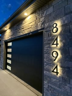 a house with a large garage door and numbers on the side of it at night