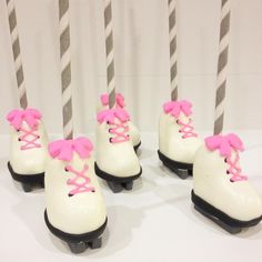 four white and pink roller skates with bows on them