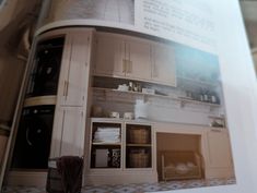 an open book shows the inside of a kitchen with white cabinets and drawers, including baskets