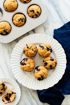 blueberry muffins are on plates next to the muffin tray