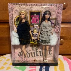 two barbie dolls are in a box on a table