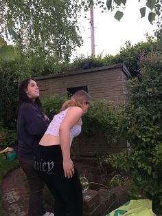 two women are standing outside in the yard, one has her back to the camera