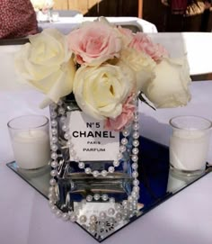 a vase with flowers and candles is on a mirrored tablecloth that says n's chanel