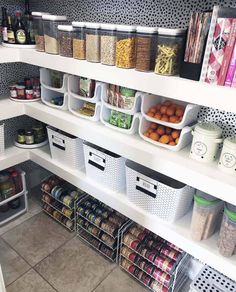 an organized pantry with bins and containers on the bottom shelf, full of food