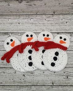 crocheted snowmen with red scarf on wooden background