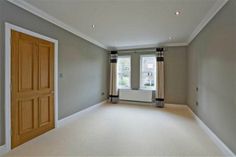 an empty room with two windows and a radiator in the corner, next to a door