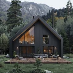 a house with a deck in front of it surrounded by trees and mountains is lit up at night